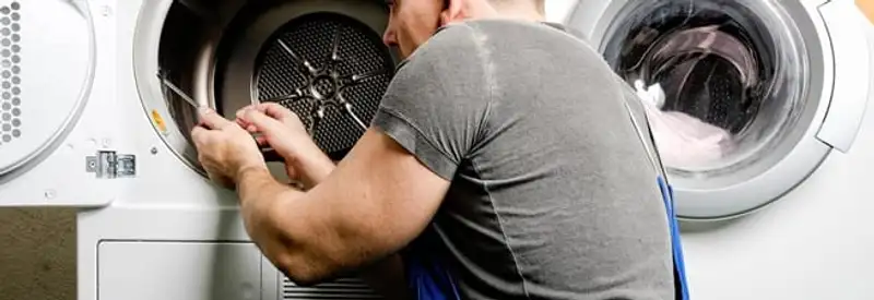 Dryer repair technician fixing a clothes dryer drum in Syracuse, NY