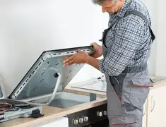Appliance repair technician installing a built-in cooktop in Syracuse, NY