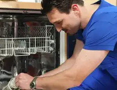 Dishwasher repair technician inspecting and servicing an open dishwasher in Syracuse, NY