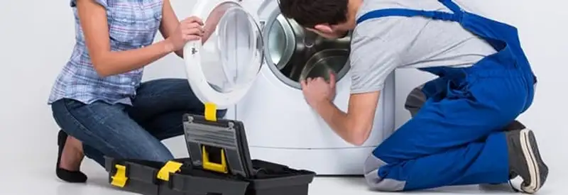 Washer repair technician inspecting a front-load washing machine with tools in Syracuse, NY