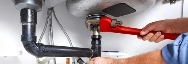 Garbage disposal repair technician tightening the sink drain and disposal connection in Syracuse, NY