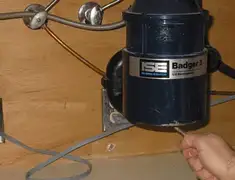 Garbage disposal repair technician tightening the mounting ring under a sink in Syracuse, NY