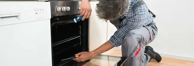 Oven repair technician inspecting and servicing an electric oven in Syracuse, NY