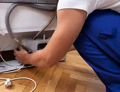 Appliance repair technician fixing refrigerator water line and connections in Syracuse, NY