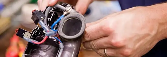 Vacuum repair technician reconnecting wiring and components in Syracuse, NY