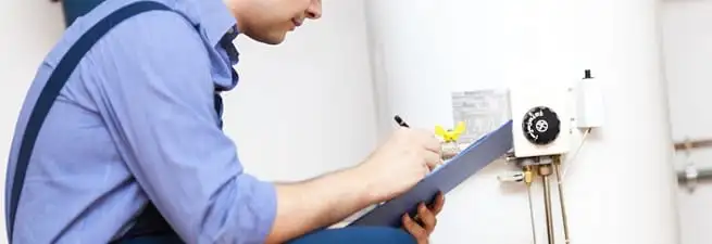 Water heater repair technician inspecting the unit and recording service notes in Syracuse, NY