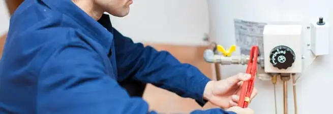 Water heater repair technician adjusting the temperature control and gas valve in Syracuse, NY